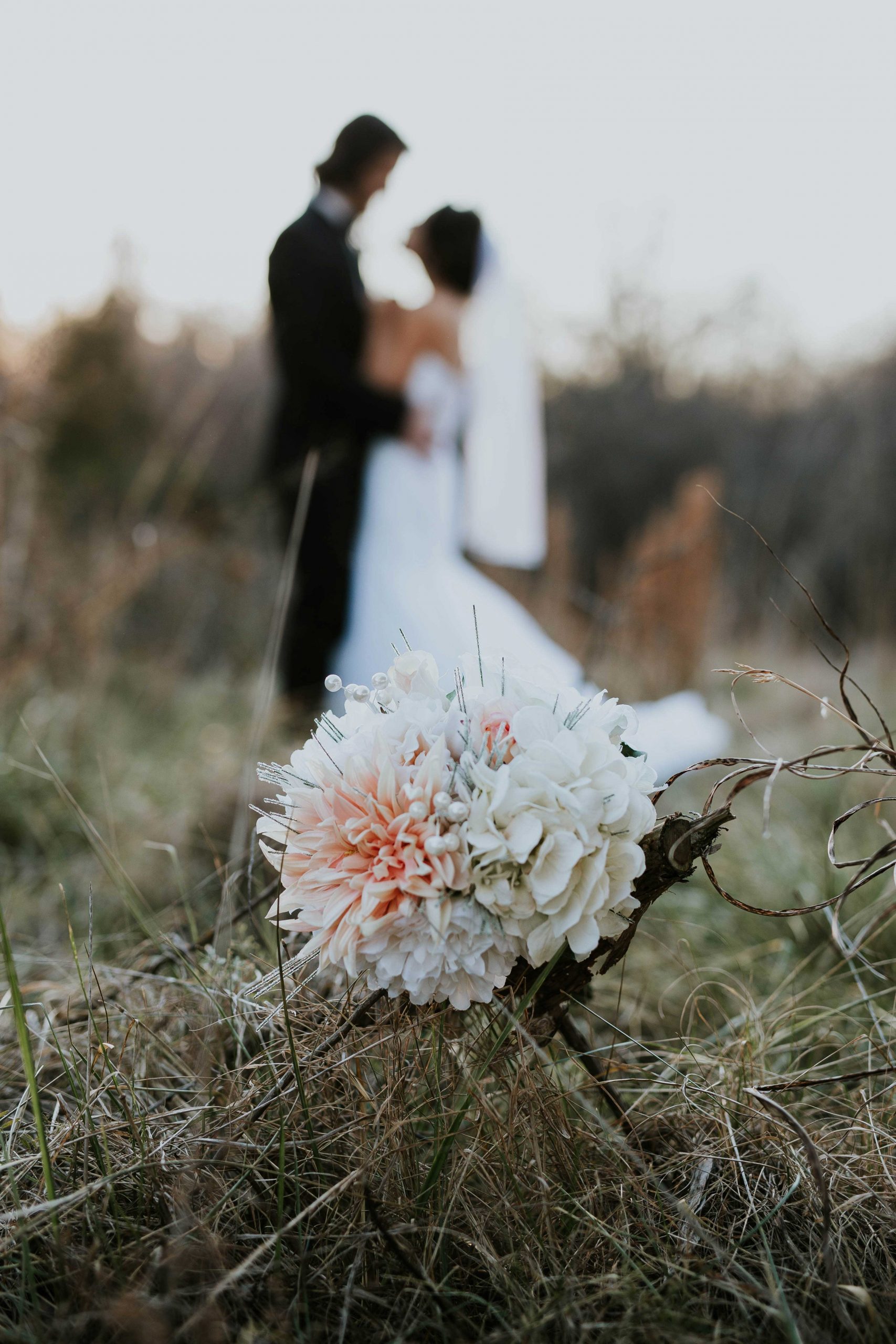 Fleur rose dans un champs avec couple marié en fond